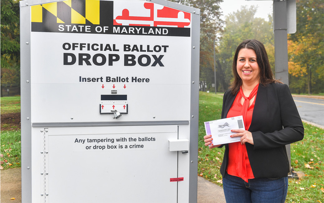 Natalie Scala standing next to a ballot drop box on campus