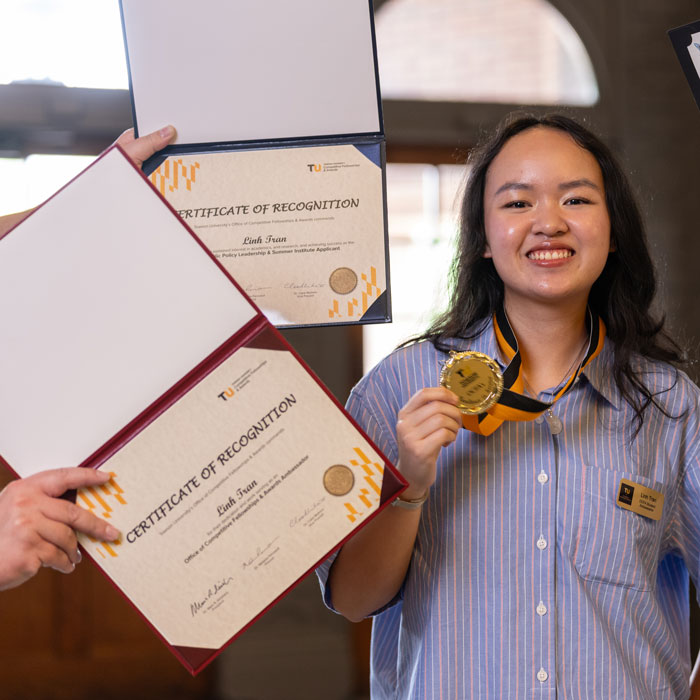 TU Student Holding Up Awards