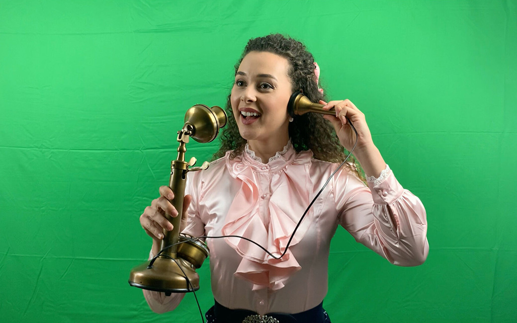 Shereen Ahmed holds up old phone in front of greenscreen
