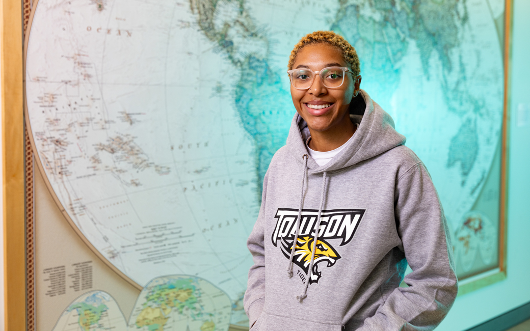 Shilah Bremond on campus in front of a map of the world