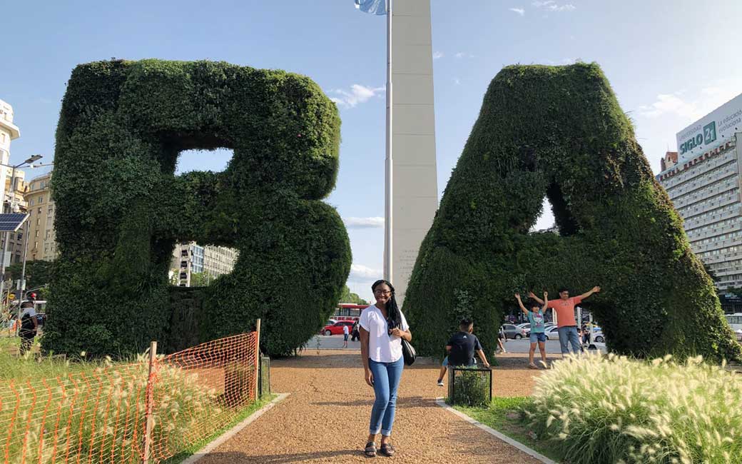 Ayomide Fashola in front of large "B" "A" hedges