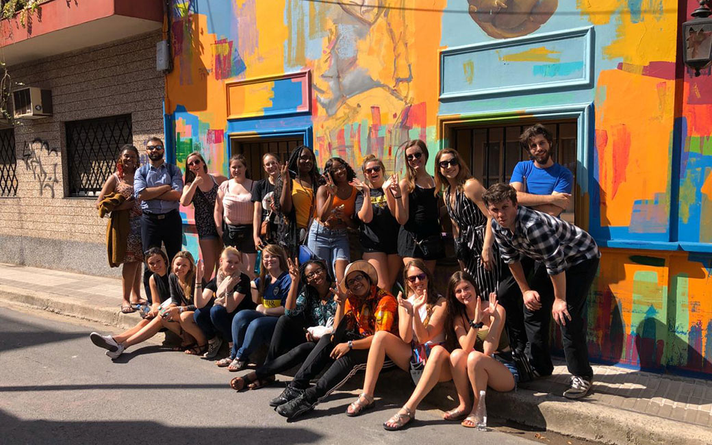 Study abroad group stands in front of building with colorful paint