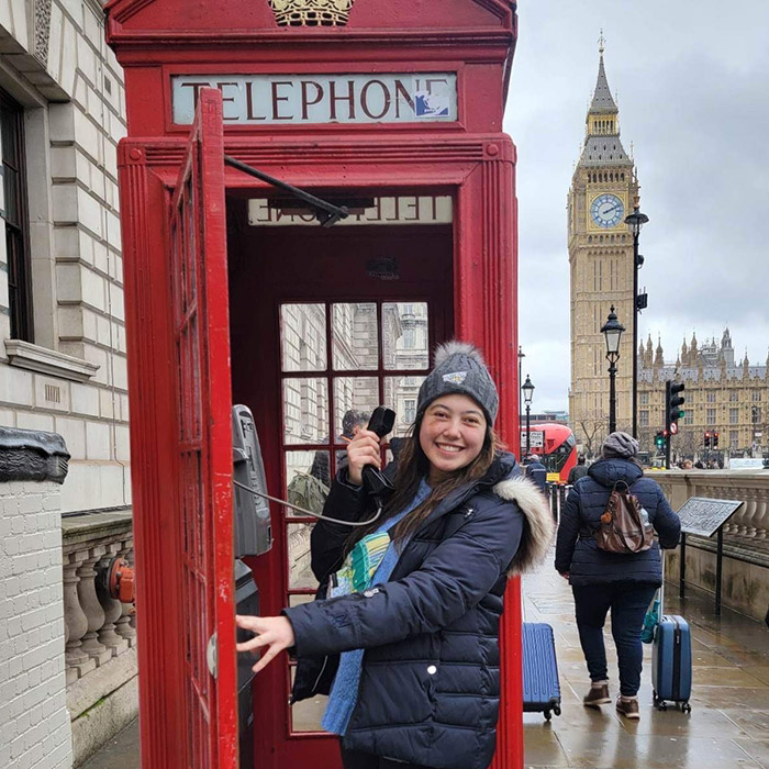 Person in red phone booth with Big Ben in background