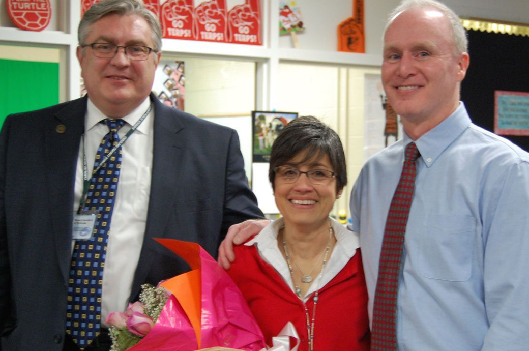 Marcia Porter, center, was named Caroline County Public Schools' 2016-17 Teacher of the Year. The Towson University Master's alumna was surprised by County Superintendent John Ewald, left, and her husband, Kenneth Porter, right. 