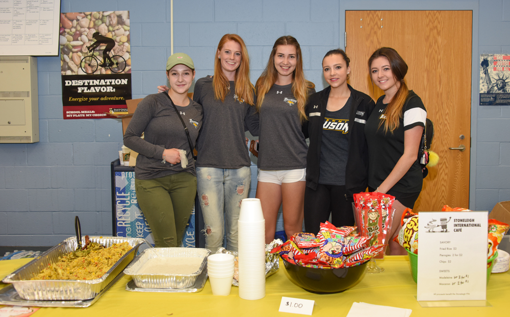 Towson University tennis team members (from left to right) Yevgeniuya Shusterman (Ukraine); Renate Van Oorschodt (Netherlands); Barbora Vasilkova (Slovakia) Sophie Lesage (France) and Nicole Shakhnazarova (England) pose behind concession stand at the Stoneleigh Elementary International Festival. The international student-athletes came to talk to students during the festival on Saturday, February 25.