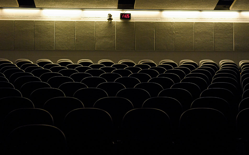 Empty lecture hall seats with dark lighting