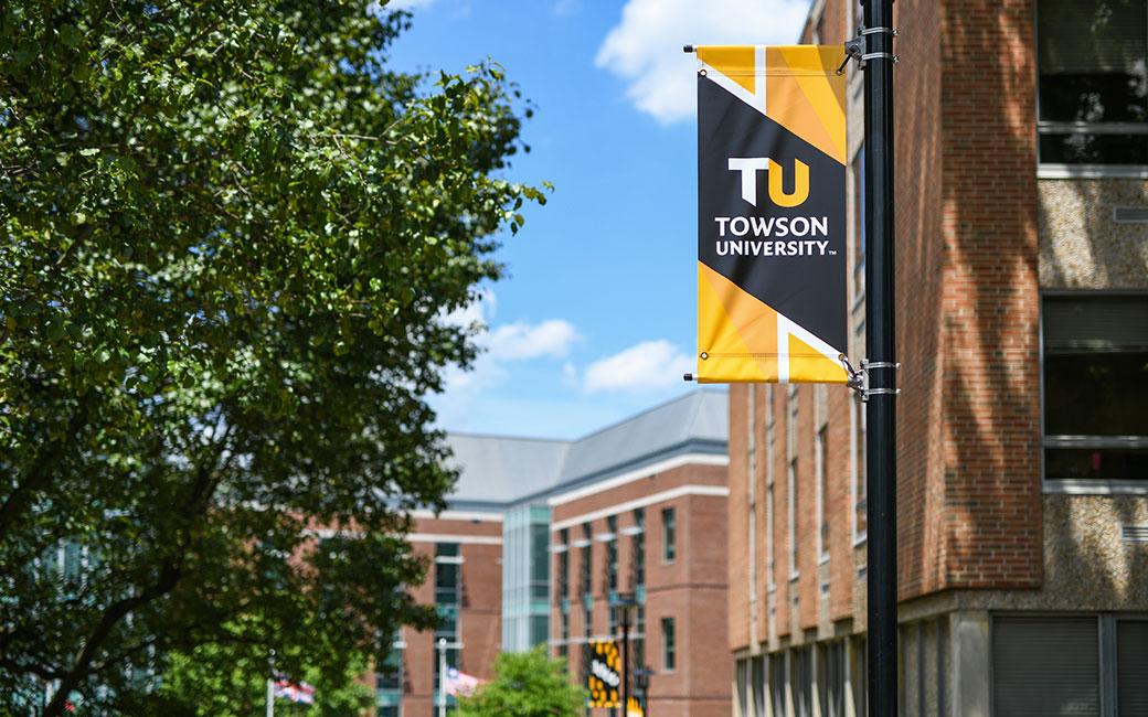 TU branded banner on lamp post with tree foliage and Liberal Arts building in background