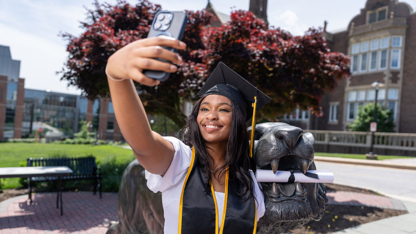 TU Student Takes Graduation Photo with the tiger statue in front of Stephens Hall 
