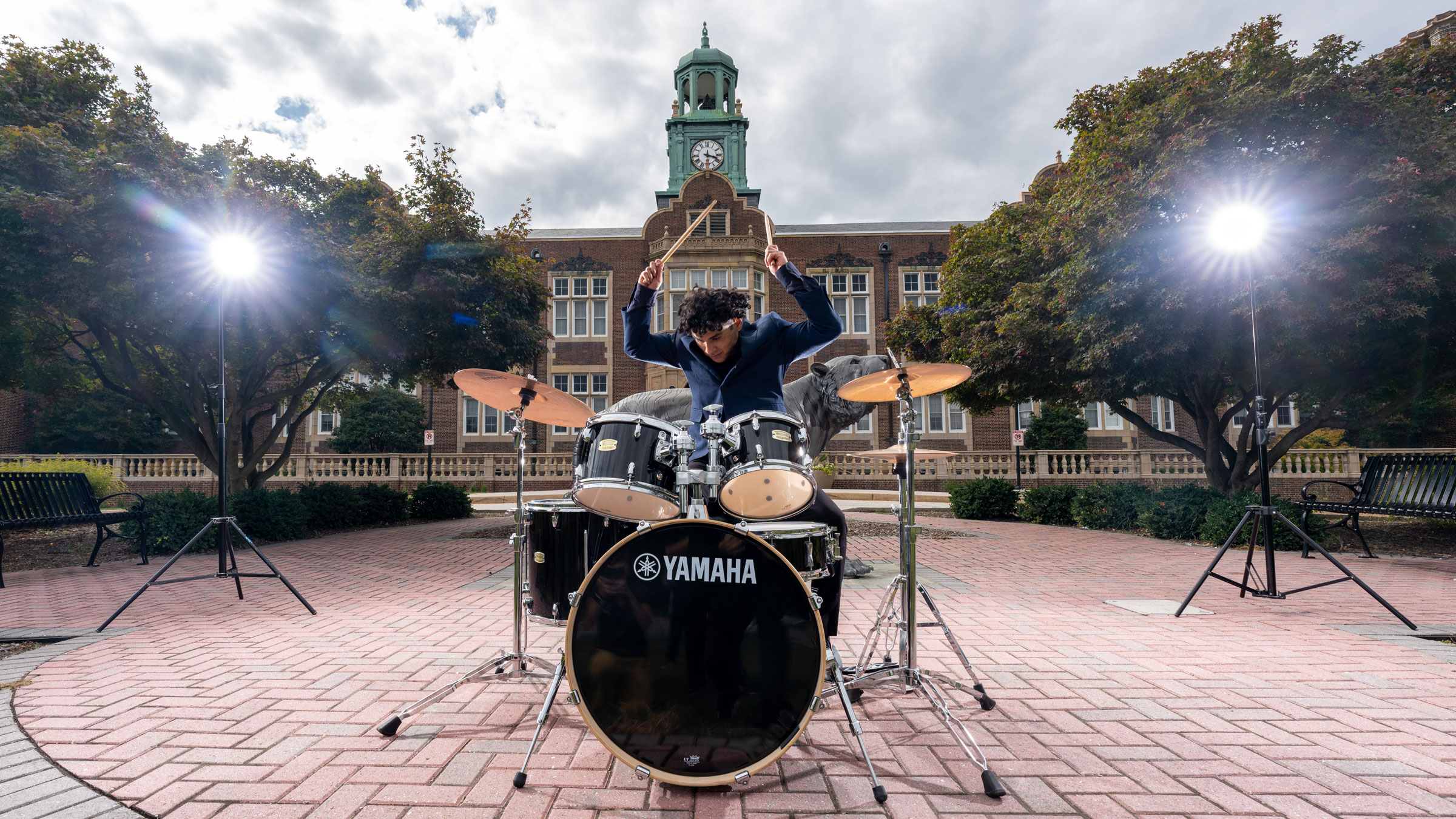 TU Senior Brandon Reyes playing drums in front of Stephens Hall 