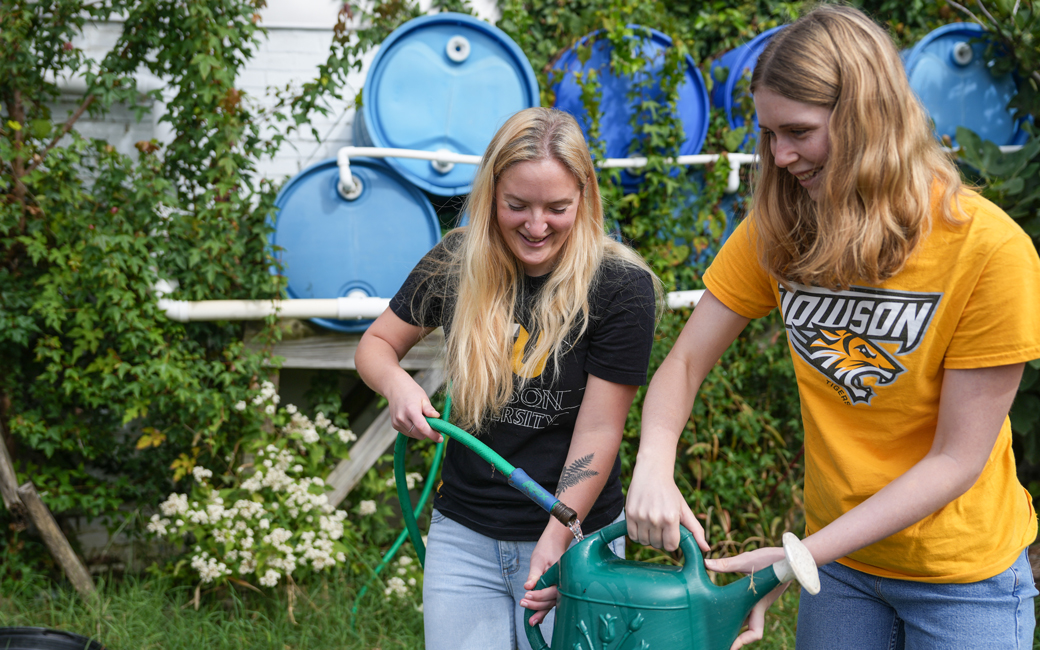 students funnel water into a watering can