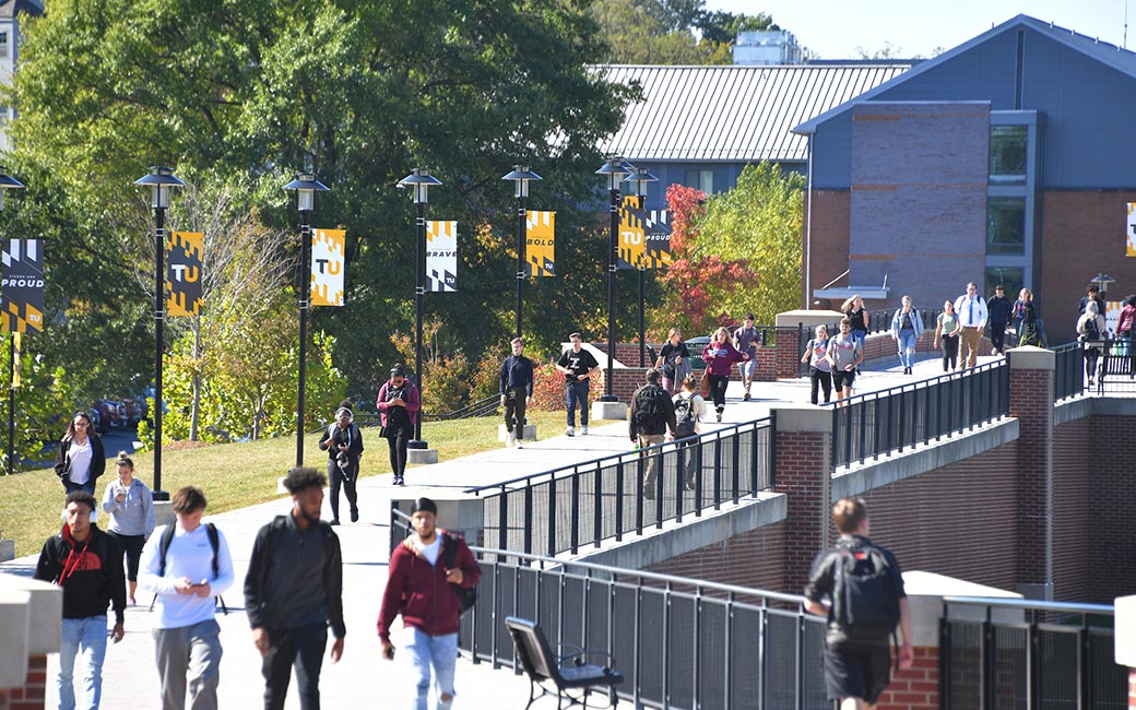 Students walking with TU banner behind