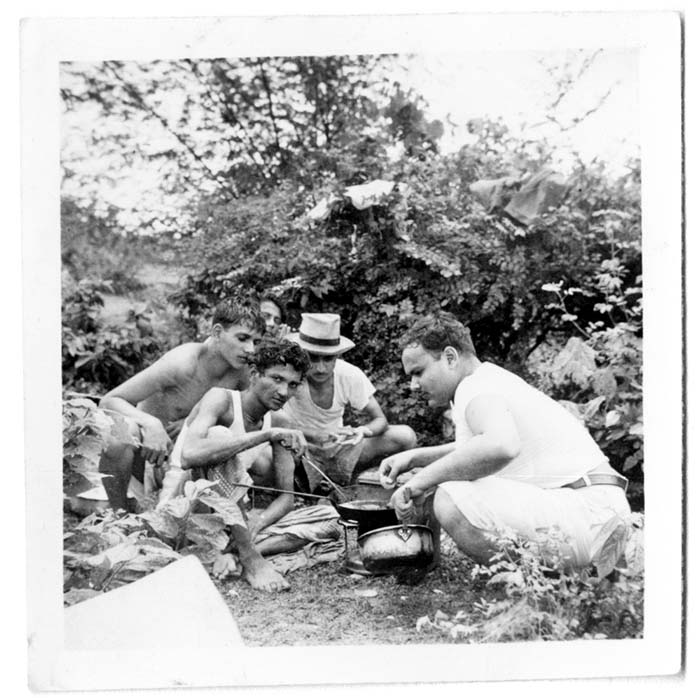 black and white photo of men in the woods looking at an object