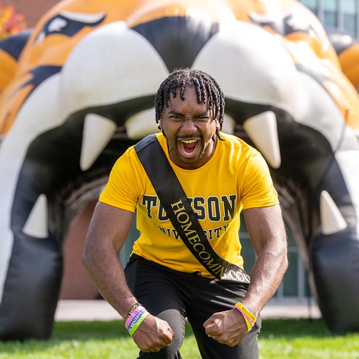 Student roaring in front of a tiger face