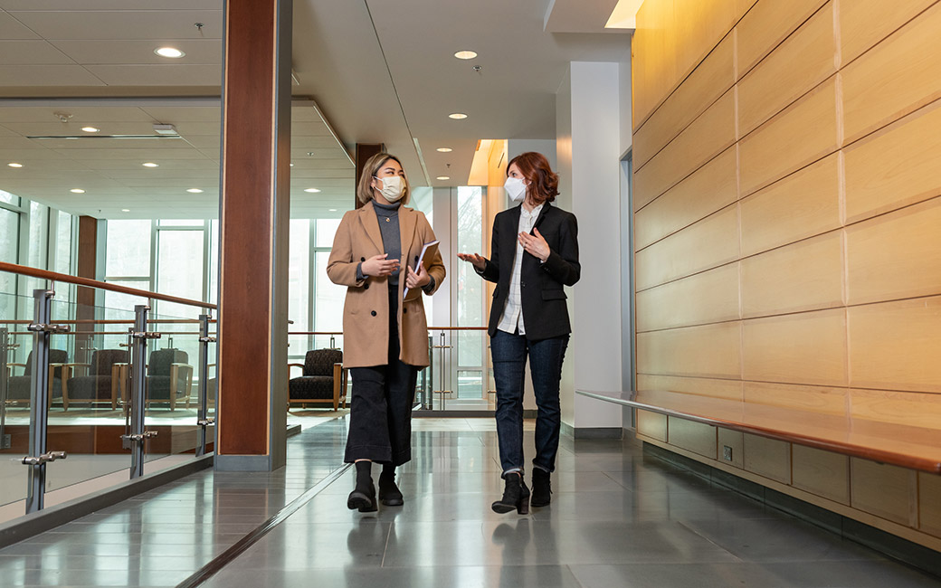 Women walking and talking in hallway with face coverings