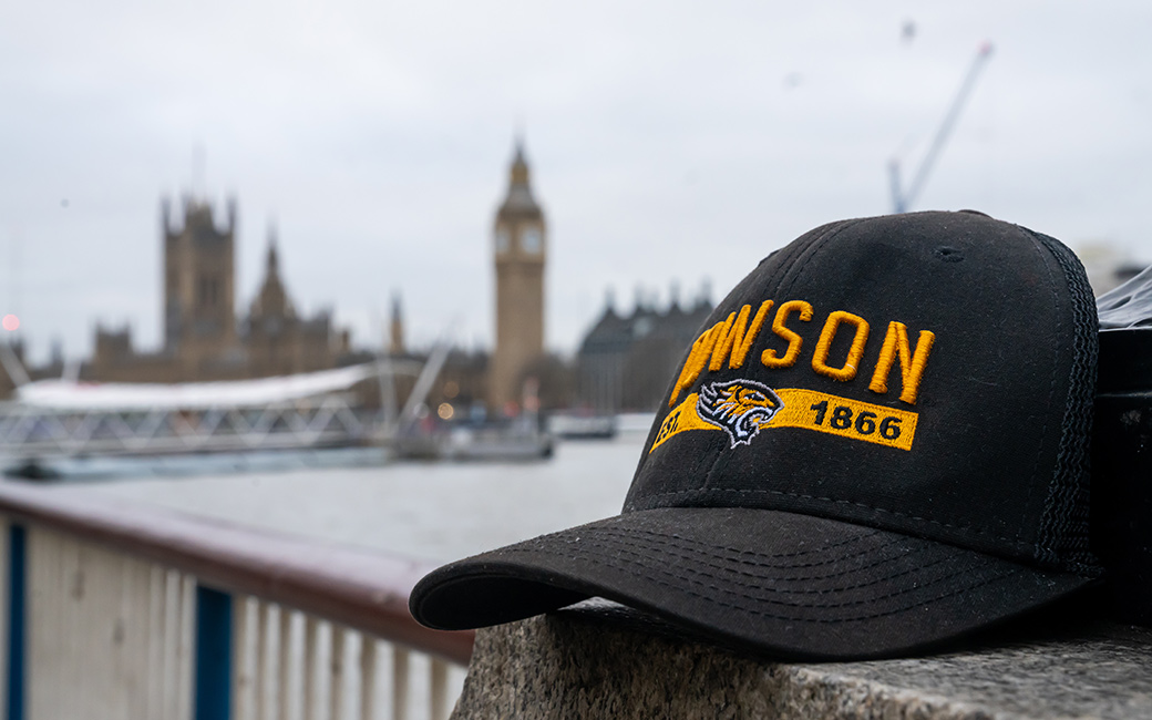 Towson University hat positioned on a ledge with London skyline in the background.