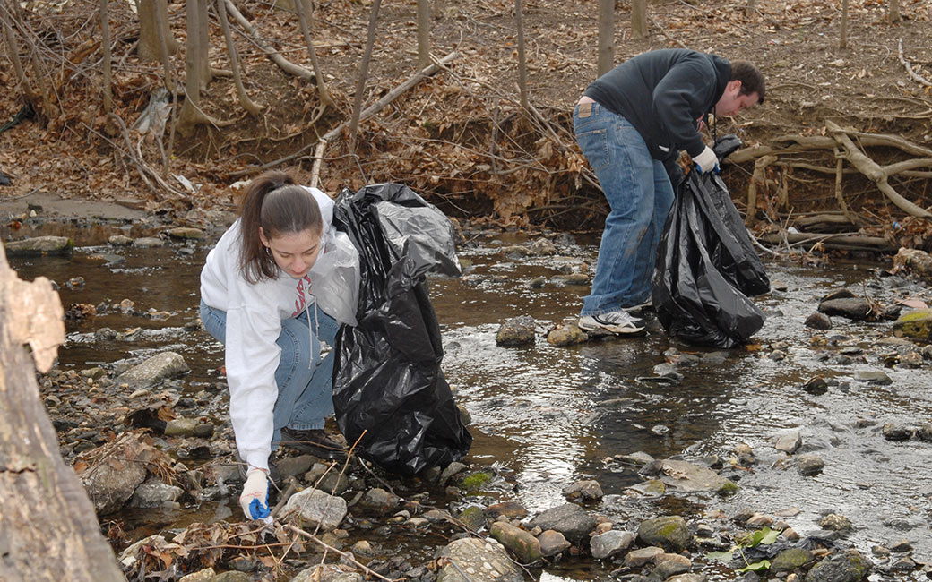  Students collect waste in creek bed.