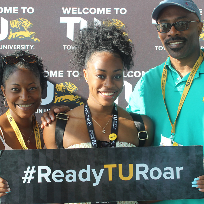 family with a ready to roar sign smiling at the camera