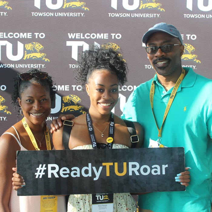 Family smiling with ready to roar sign