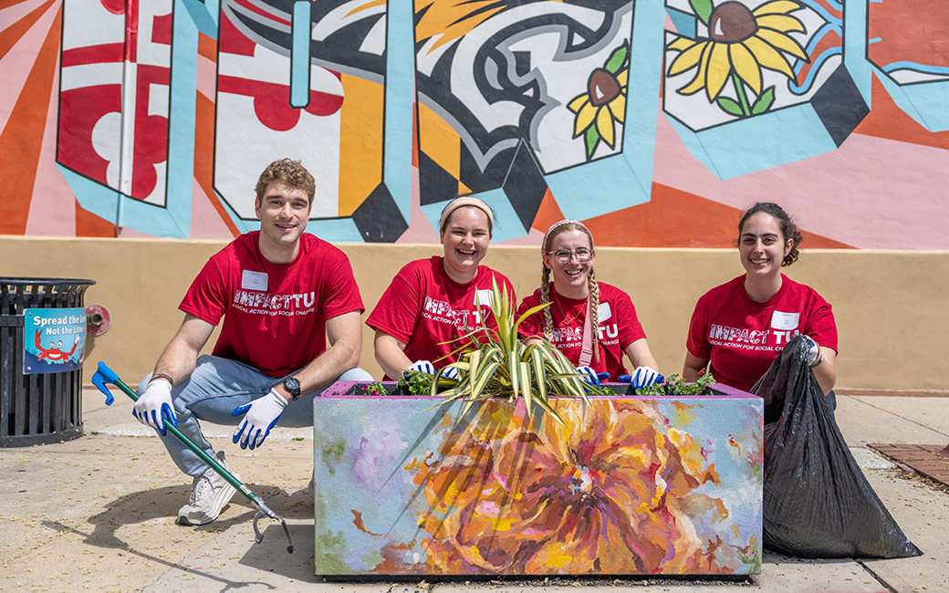 Student posing behind a planter.