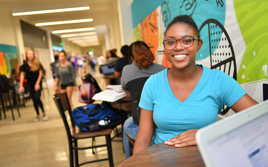 An image of a student sitting at a table in an academic building