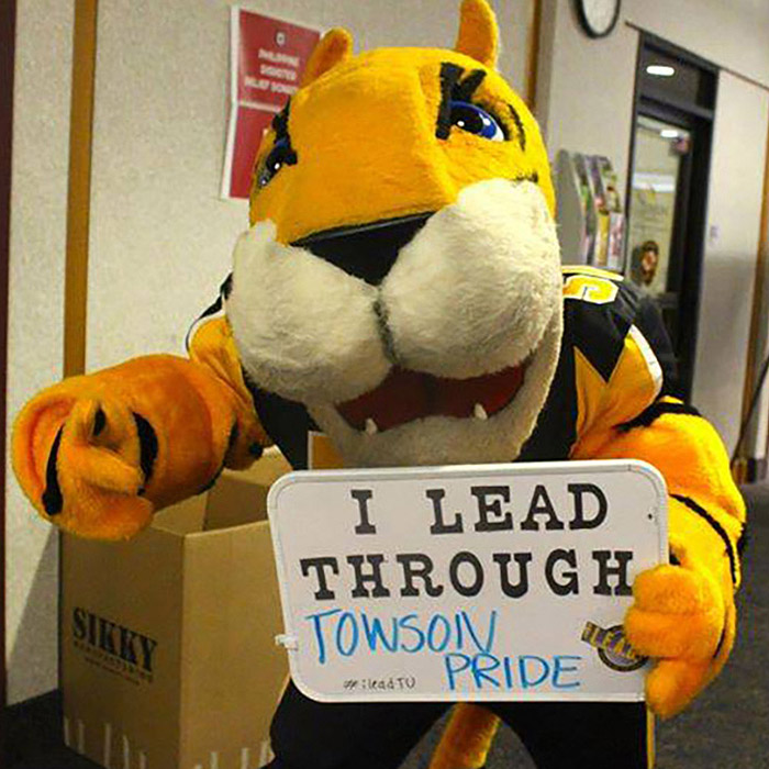 Doc holding a sign that reads "I lead through Towson Pride."