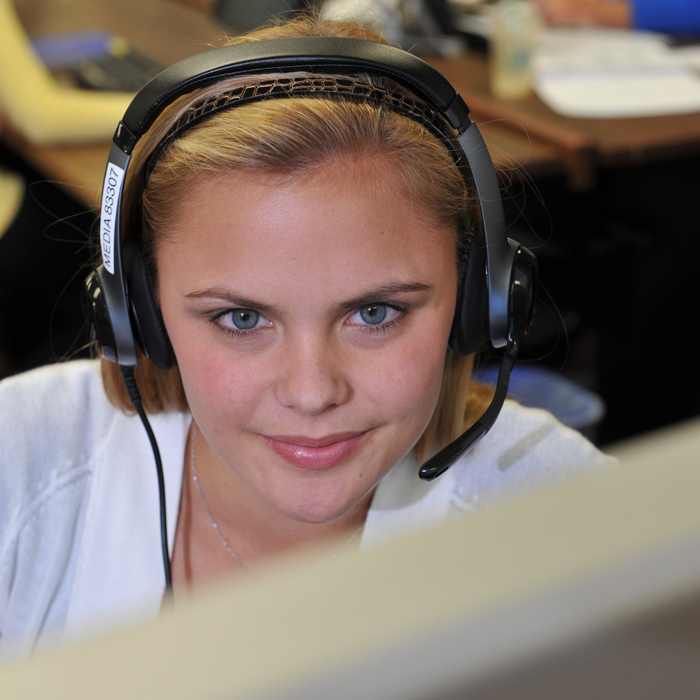 female student looking at camera from behind computer monitor