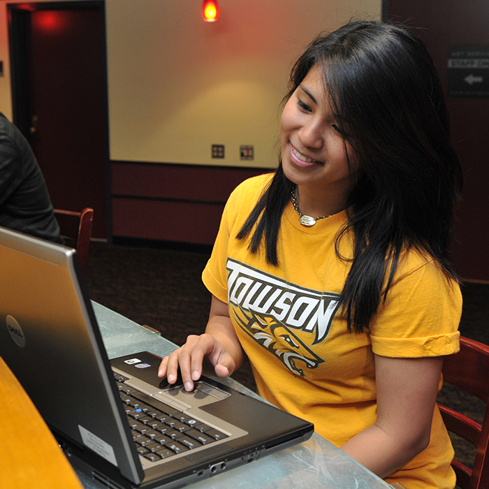 female student looking at camera from behind computer monitor